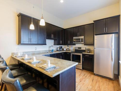 a kitchen with black cabinets and a white refrigerator at Modern Condos near French Quarter & Bourbon Street in New Orleans