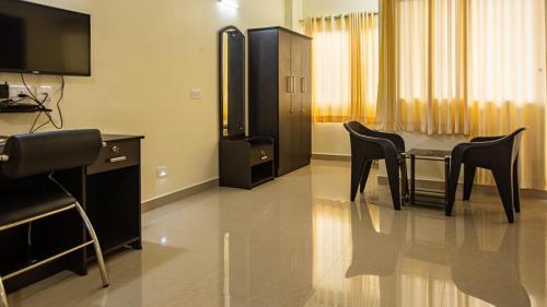 a room with a table and chairs and a television at Woodside residency in Thekkady