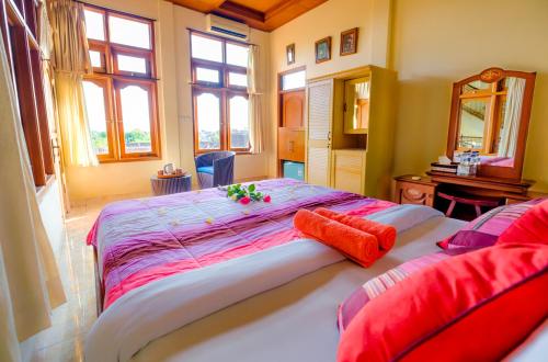 - une chambre avec un grand lit et des oreillers rouges dans l'établissement Bali Spring Cottages, à Ubud