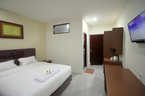 a bedroom with a white bed and a flat screen tv at Grand Mahoni Hotel in Banda Aceh