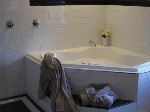 a bath tub in a bathroom with a robe at Cobblers Cottage B&B in Willunga