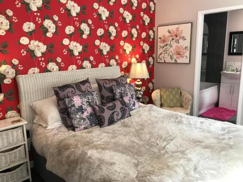 a bedroom with a bed with a red wall with flowers at Blackpool Holiday Lets -GF Regent Road in Blackpool