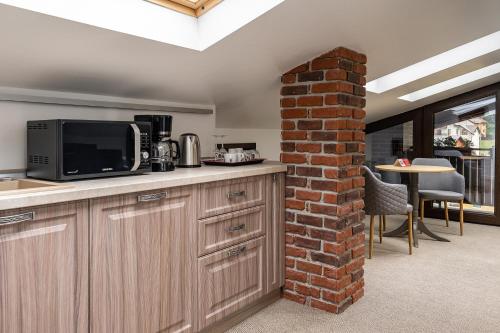 a kitchen with a microwave and a brick wall at VILA NORBE in Buşteni