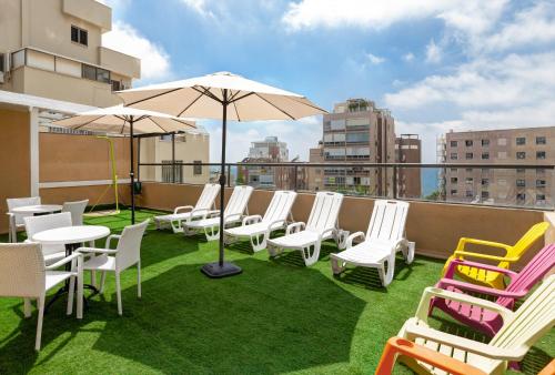 a balcony with chairs and tables and an umbrella at Mizpe Yam Boutique Hotel in Netanya