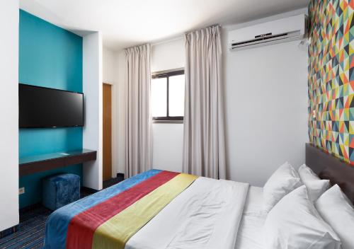 a hotel room with a bed and a flat screen tv at Mizpe Yam Boutique Hotel in Netanya