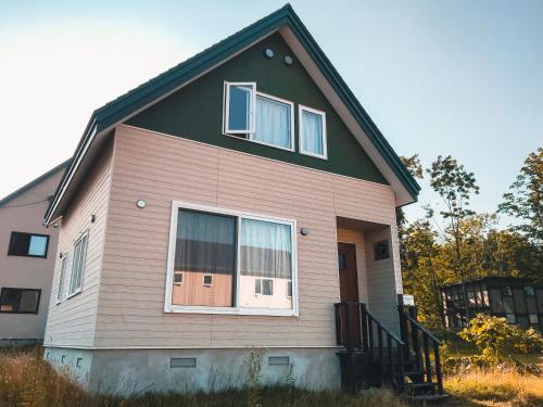 a house with a green roof and white windows at Trailside Apartments Niseko in Kutchan