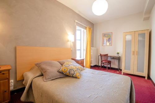 a bedroom with a bed and a table and a window at Hôtel Le Foch in Beaune