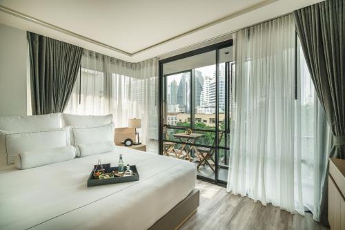 a bedroom with a large bed and a large window at Tastoria Collection Sukhumvit - SHA Extra Plus in Bangkok