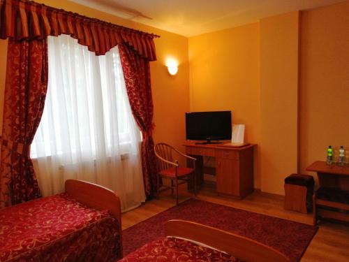 a room with a bed and a tv and a window at Hotel Grodzki in Sandomierz