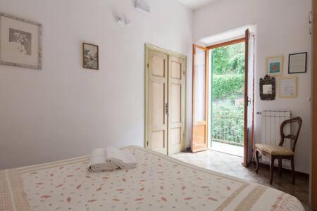 a white bedroom with a bed and an open door at Ca' de Capun in Manarola