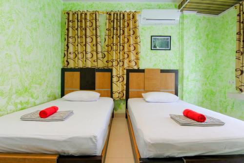 two beds in a room with red pillows on them at Yani Homestay in Padang