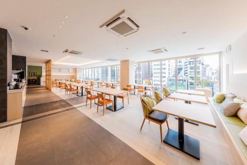 a cafeteria with tables and chairs and windows at Via Inn Prime Shinsaibashi Yotsubashi in Osaka