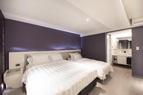 a bedroom with a large bed with a blue wall at Saual Keh Hotel in Taipei