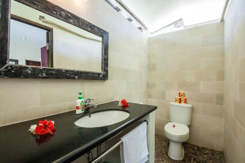 ein Badezimmer mit Waschbecken, Toilette und Spiegel in der Unterkunft Rumah Antony in Gili Trawangan