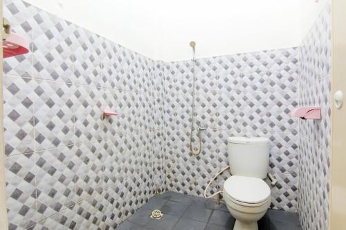 a bathroom with a toilet and a tiled wall at Trans Bandara Residence in Sungairampah