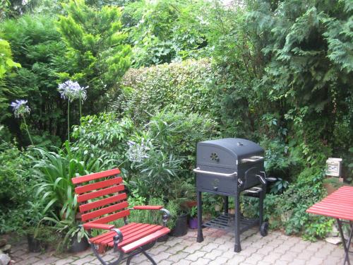 a grill and a red bench in a garden at Flair Apartmanház in Eger
