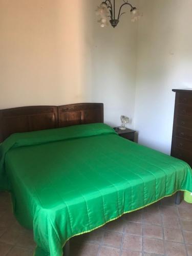 una cama con una cubierta verde en una habitación en Residenza Le Querce Bilocale, en Fossato di Vico