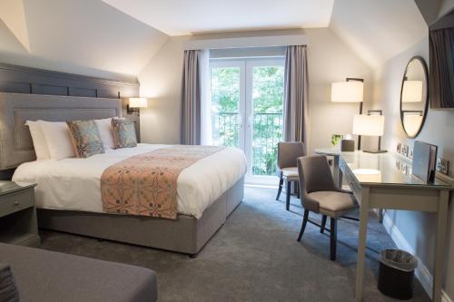 una camera d'albergo con letto, scrivania e specchio di Llechwen Hall a Pontypridd