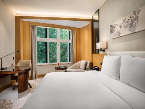 a bedroom with a bed and a desk and a window at Xiamen C&D Hotel-Free Welcome Snacks-Oasis Garden in Xiamen