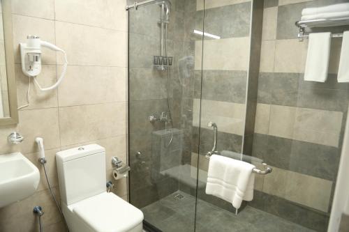 a bathroom with a shower with a toilet and a sink at Uptown Hotel Apartment Fujairah By Gewan in Fujairah