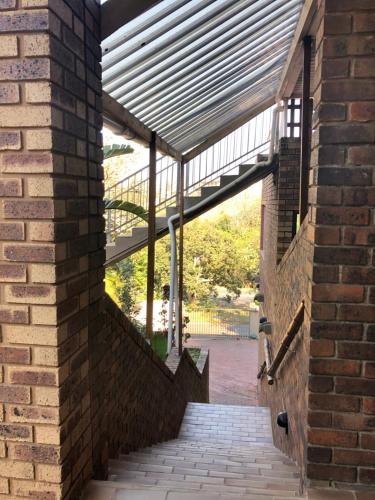 a brick building with a staircase with a roof at Seaside Lodge B&B in Ballito