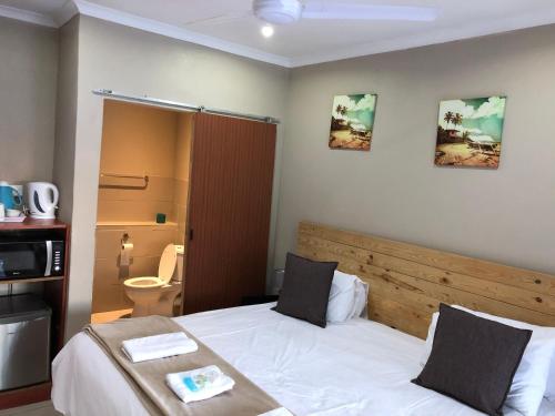 a bedroom with a white bed with a wooden headboard at Seaside Lodge B&B in Ballito