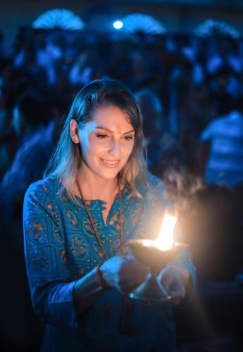 a woman holding a lit candle in her hand at GANGA KINARE- A Riverside Boutique Resort, Rishikesh in Rishīkesh