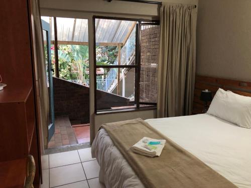 a hotel room with a bed and a view of a balcony at Seaside Lodge B&B in Ballito