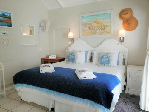 a bedroom with a blue and white bed with towels on it at Eastbury Cottage in Hermanus