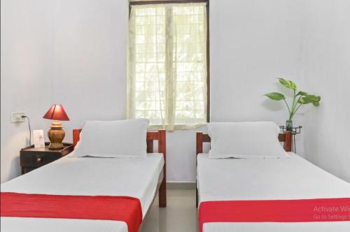 two beds in a room with a table and a window at Marari Bethsaida Homestay in Shertallai