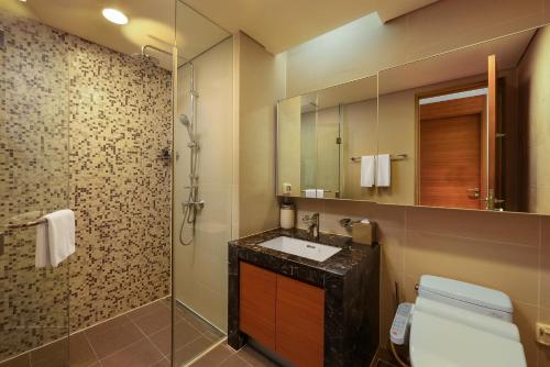 a bathroom with a sink and a shower with a mirror at Lotte The Residence in Hanoi