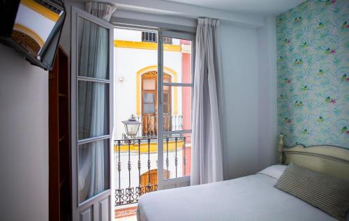 Schlafzimmer mit einem Bett und einem Fenster mit einem Balkon in der Unterkunft Hostal San Francisco in Sevilla