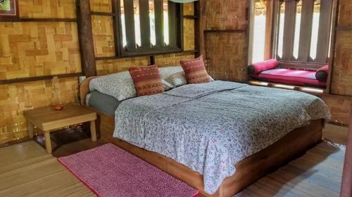 a bedroom with a bed and a table and windows at Sang Tong Huts in Mae Hong Son