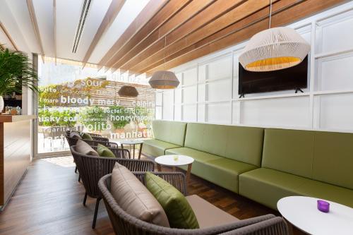 a restaurant with a green couch and chairs at Aimia Hotel in Port de Soller