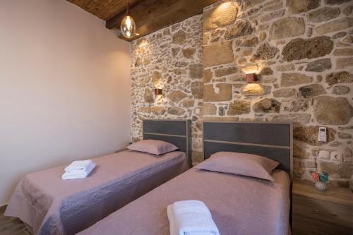 two beds in a room with a stone wall at Doro Villas in Drapaniás