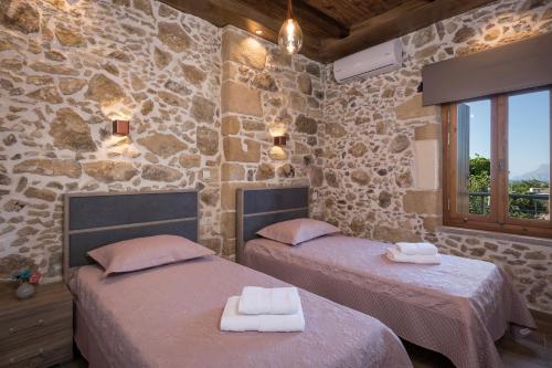 two beds in a room with stone walls at Doro Villas in Drapaniás