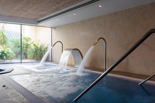 a hot tub with two water fountains in a room at Aimia Hotel in Port de Soller