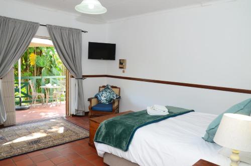 a bedroom with a bed and a tv and a patio at Cuckoos Nest Guest House in Louis Trichardt
