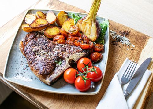 a plate of steak and potatoes and vegetables on a table at Ferienresort Texas MV in Kirch Jesar