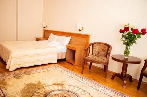 a bedroom with a bed and a table and a chair at Altyn Dala Hotel in Astana