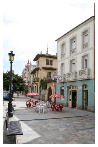 a street with tables and chairs with red umbrellas at Hostal Galicia in Ribadeo