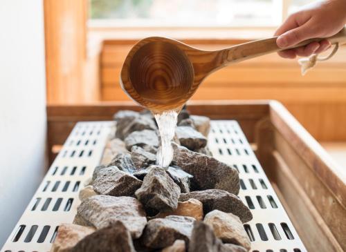 a person with a wooden spoon cooking food on a grill at Sporthotel Bruurs in Baarle-Nassau