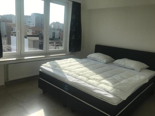 a bed in a room with two windows at Apartment Thalassa5@sea in Ostend