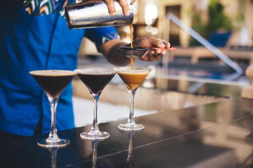 a bartender making three cocktails in martini glasses at The Niche Bali in Legian
