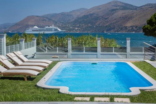 a swimming pool with chairs and a cruise ship in the background at Lighthouse Villas Kefalonia in Argostoli