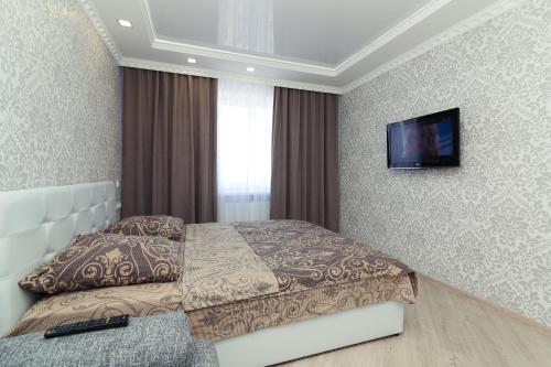 a bedroom with a bed and a tv on the wall at Luxury apart-hotel on Kondrateva street in Sumy