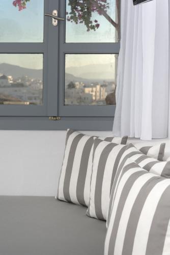a bed with black and white pillows in front of a window at Iliada Suites in Naxos Chora