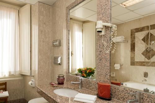 a bathroom with a sink and a large mirror at Bettoja Hotel Massimo d'Azeglio in Rome