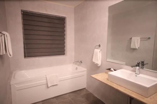 a bathroom with a tub and a sink and a mirror at PrideInn Plaza Nairobi Airport in Nairobi