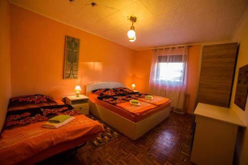 two beds in a bedroom with orange walls and a window at Apartments Vila Palma in Medulin